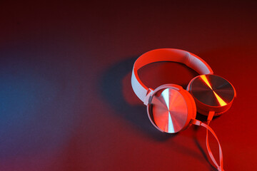 White, over-the-ear headphones with a wire on a colored, dark background.