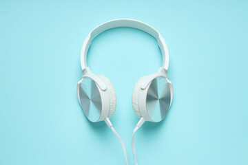 White, over-the-ear headphones with a wire on a blue background.