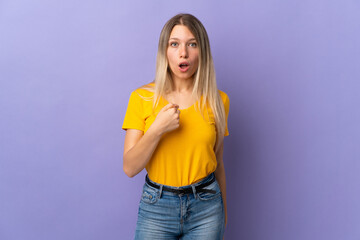 Young blonde woman isolated on purple background pointing to oneself