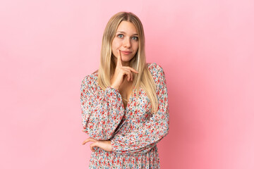 Young blonde woman isolated on pink background having doubts and thinking