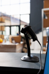 Selective focus of stockroom scanner standing on counter desk in storage room, in background african american worker preparing packages for delivery. Supervisor working at clients online orders