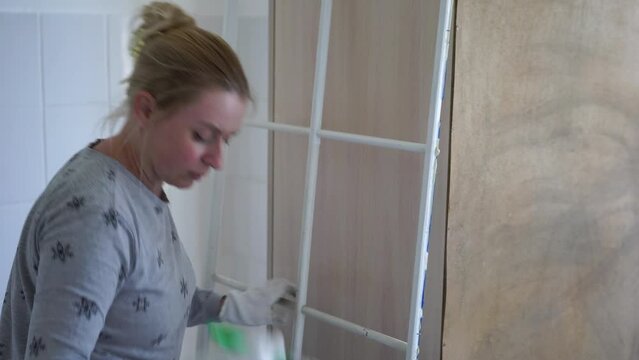 Repair and Renovation work. Adult woman painting wall using brush dipped in white paint. Apartment redecoration and home construction while renovating. Close-up of painting the item with white paint.