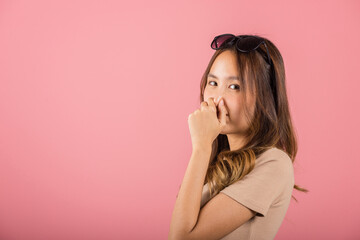 Asian beautiful young woman unhappy what a smell disgust expression squeezing nose with fingers....