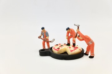 miniature figurines of men at work with a huge pizza on a tray
