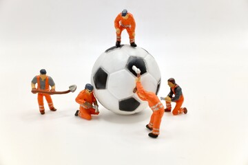 miniature figurines of a men at work team working on a soccer balloon