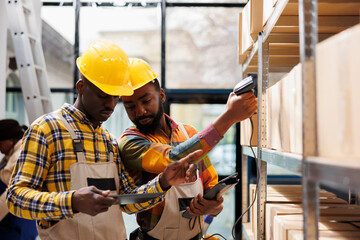 African american warehouse managers scanning parcels before shipment. Post office storehouse workers doing merchandise inventory using scanner and checking barcode in digital tablet