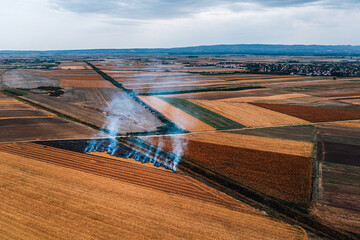 Wheat field stubble burning after the harvesting of grains is one of the major causes of air pollution, aerial shot from drone pov