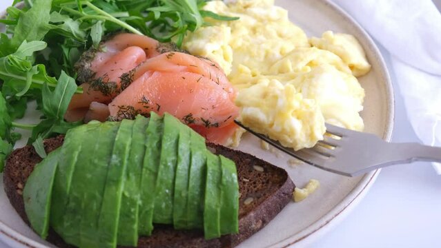 Keto breakfast with salmon toast, avocado, scrambled egg on white background.
