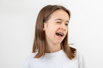 Portrait of a teenage girl winking cheerfully on a white background isolated.