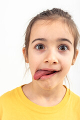A little girl grimaces with her tongue hanging out on a white background. - obrazy, fototapety, plakaty