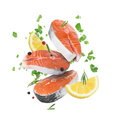 Fresh salmon steaks, spices and lemon slices falling on white background