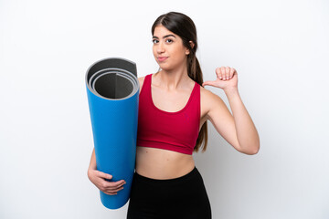 young sport woman going to yoga classes while holding a mat isolated on white background proud and...