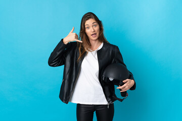 Young Ireland woman holding a motorcycle helmet isolated on blue background making phone gesture....