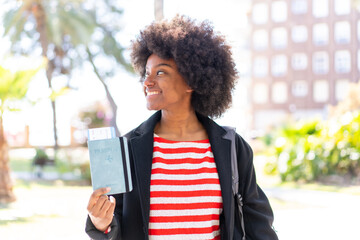 African American girl at outdoors holding a passport with happy expression