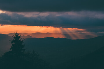 Obraz premium Sunset with rays of light falling from the sky. Stunning alpine landscape with golden skies and dramatic clouds
