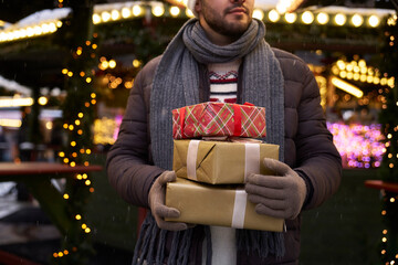 Unrecognizable caucasian man carrying a pile of Christmas presents