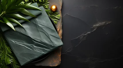 Foto op Canvas Folded black napkins on black stone background with green leaves. Eco friendly Mock up for display or montage of dishes, food or washing detergent. © alexkich