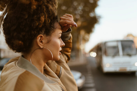 Young woman touching forehead at street