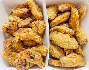 closeup fried chicken legs and wings in a white paper box