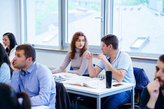 Diverse students discussing at desk in education training class