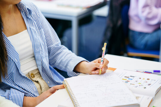 Student writing in notebook at desk in classroom