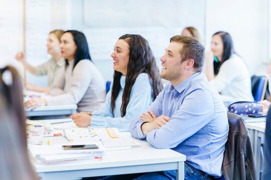 Smiling multi-ethnic students sitting at desk and studying in classroom