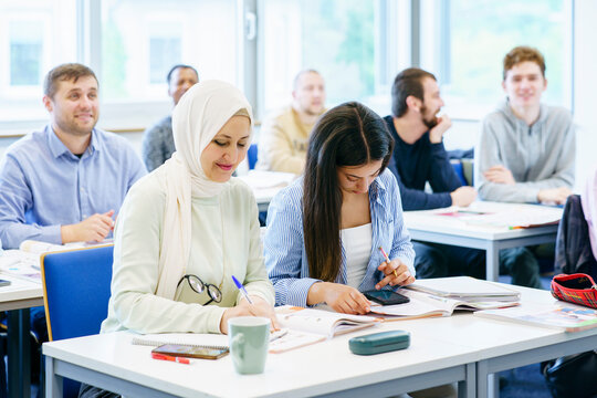 Multi-ethnic students with books at desk studying in ed training class
