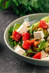 Portion of fresh greek salad on grey background