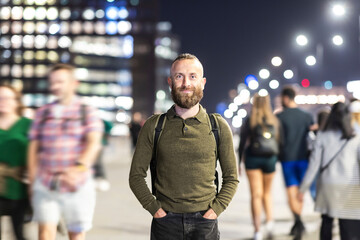 Smiling man standing with hands in pockets in city