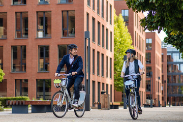 Spouses commuting through the city, riding bike on street. Middle-aged city commuters traveling...