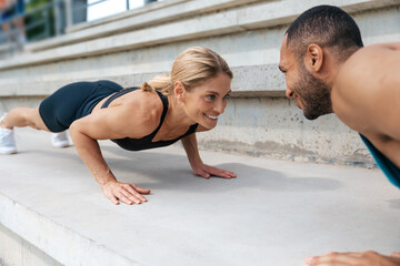Fototapeta na wymiar Athletic man and woman training doing push-ups outdoor.