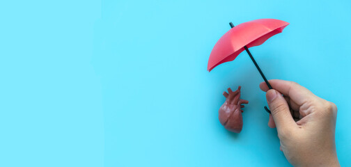 World Heart Day , world hypertension day, Cardiology concept. Healthcare banner. Hand holding umbrella over a heart model.