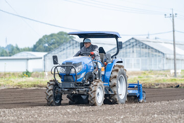 Obraz premium トラクターを運転するシニア男性
