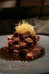 Grilled and sliced beef with sauce on a black plate, close-up