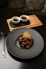 Grilled and sliced beef with sauce on a black plate, close-up