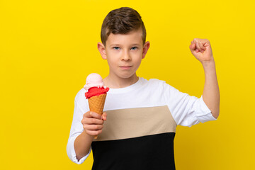 Little caucasian boy with a cornet ice cream isolated on yellow background doing strong gesture