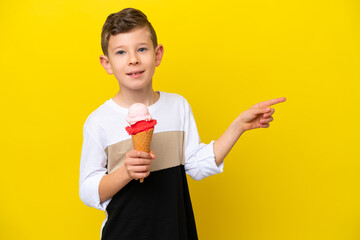 Little caucasian boy with a cornet ice cream isolated on yellow background pointing finger to the...