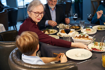 Grandparents and grandson sitting at a festive table in the restaurant