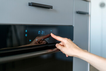 Selective focus on woman hand pressing on sensor button on domestic modern kitchen equipment