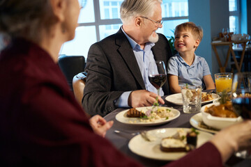 Happy old man and little boy looking at each other in the restaurant