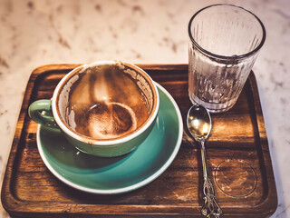 Hot cappuccino coffee in a drinking glass Placed on the table in a warm atmosphere. There is space...