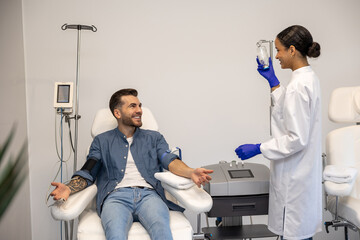 Smiling man doing insertion of drip in clinic.