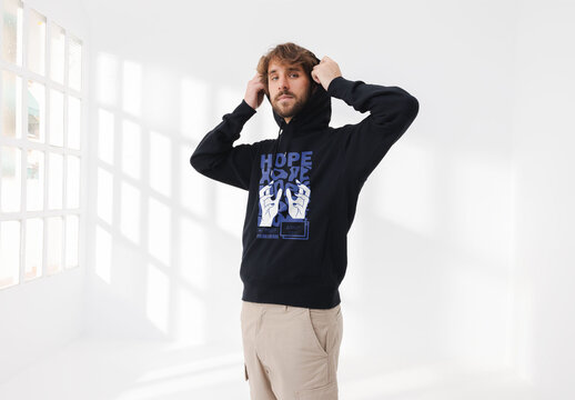 Mockup of man wearing customizable hoodie, putting hood up