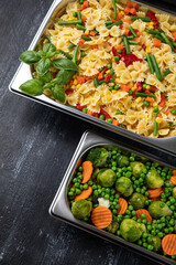 Containers with pasta and vegetables in the kitchen