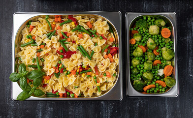 Containers with pasta and vegetables in the kitchen