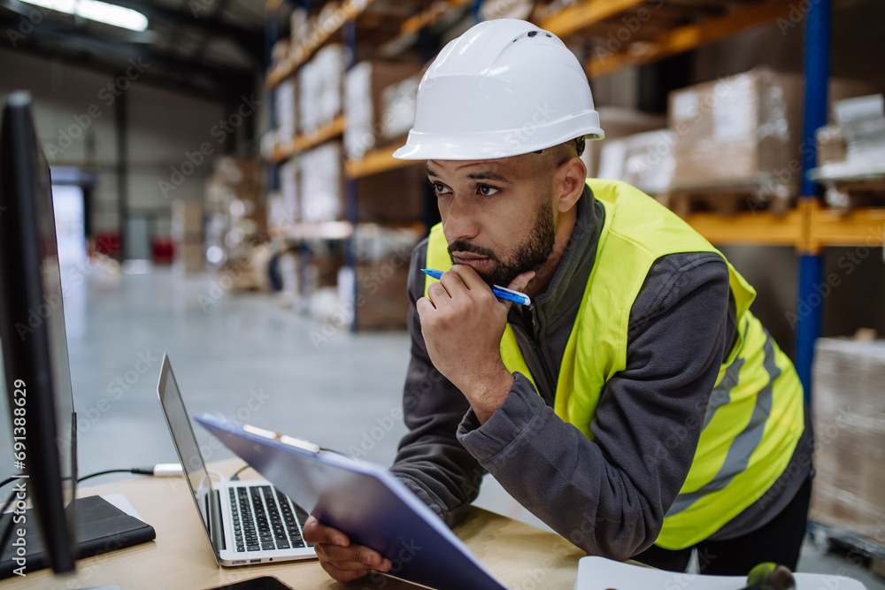 Wall mural warehouseman checking delivery, stock in warehouse on computer, pc. warehouse manager using warehous