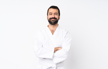 Young man doing karate over isolated white background keeping the arms crossed in frontal position