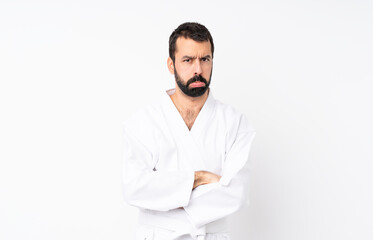 Young man doing karate over isolated white background with sad and depressed expression