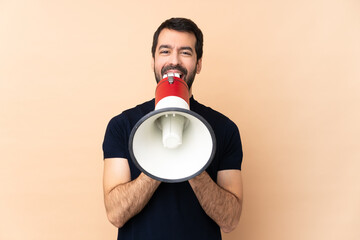 Caucasian handsome man over isolated background shouting through a megaphone