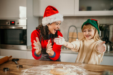 Mother and daughter playing with flour in the kitchen